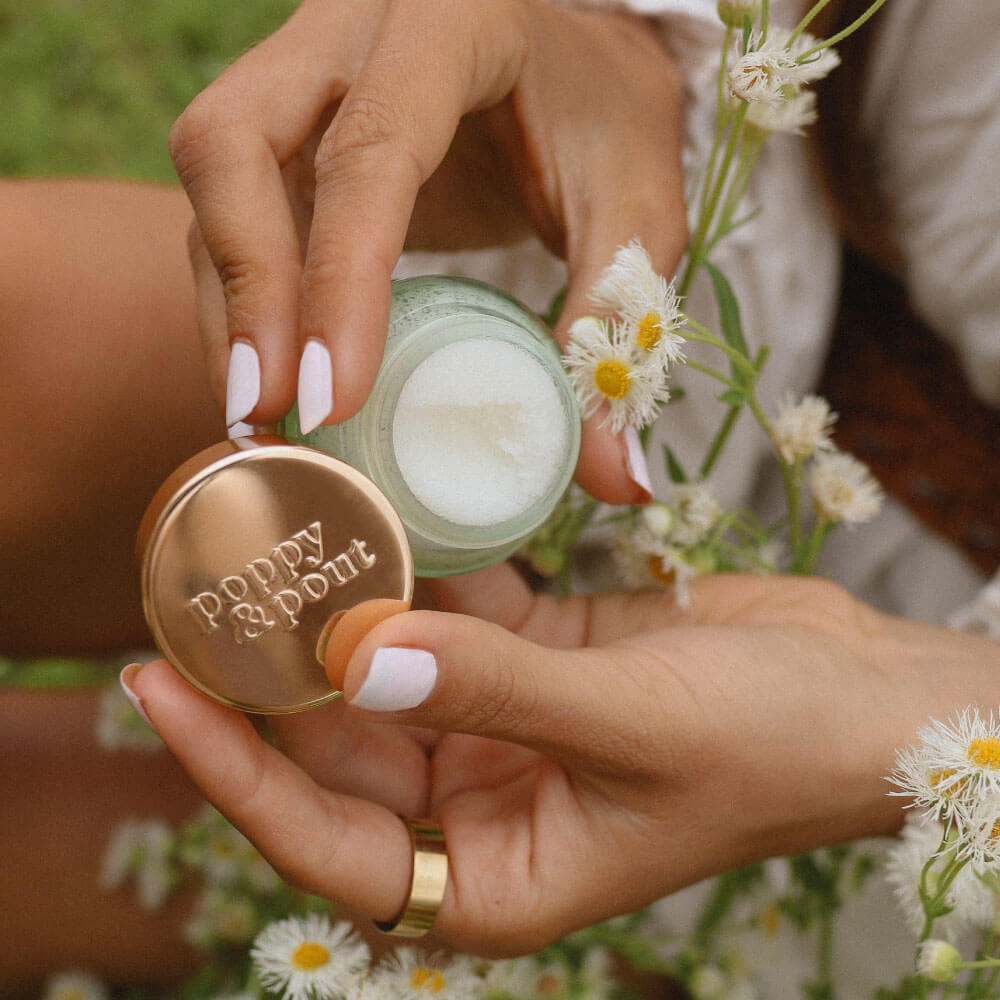 Girl holding 100% Natural Lip Scrub in flower field