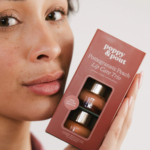 Close-up of woman holding Poppy & Pout pomegranate peach lip care trio box