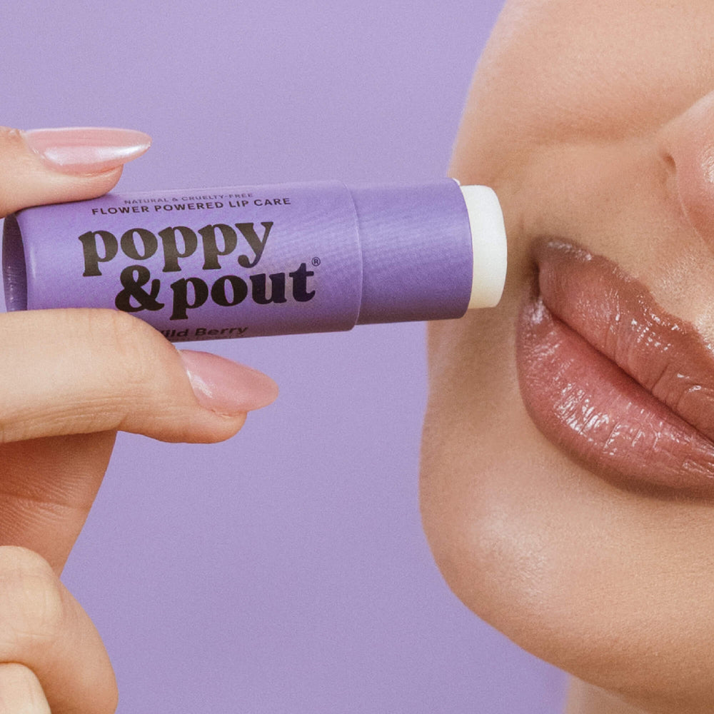Wild berry lip balm tube, held near glossy lips, purple tube